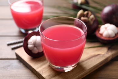 Delicious fresh mangosteen juice in glass on wooden table