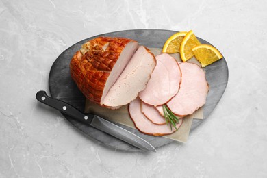 Photo of Delicious sliced ham with orange and rosemary on grey marble table, top view