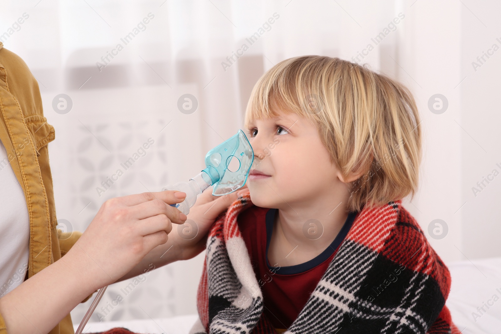 Photo of Mother helping her sick son with nebulizer inhalation at home