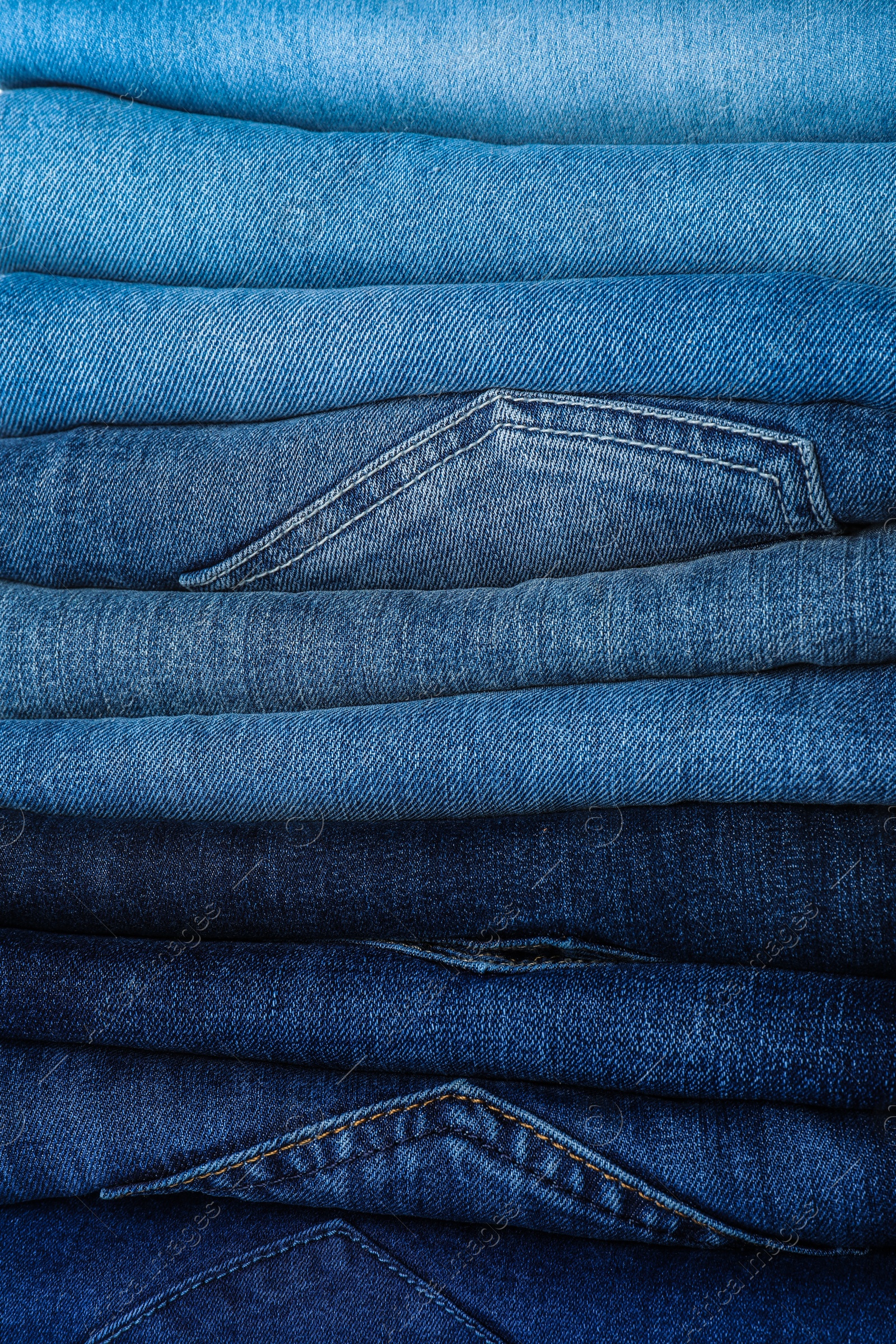 Photo of Stack of different jeans as background, closeup