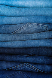 Photo of Stack of different jeans as background, closeup