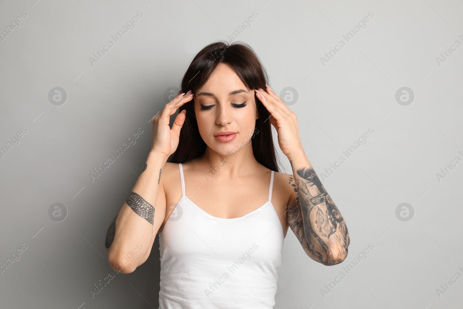 Photo of Beautiful woman with tattoos on arms against grey background