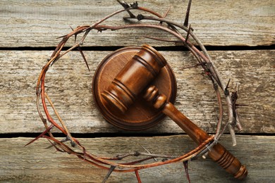 Photo of Crown of thorns and judge gavel on wooden table, flat lay