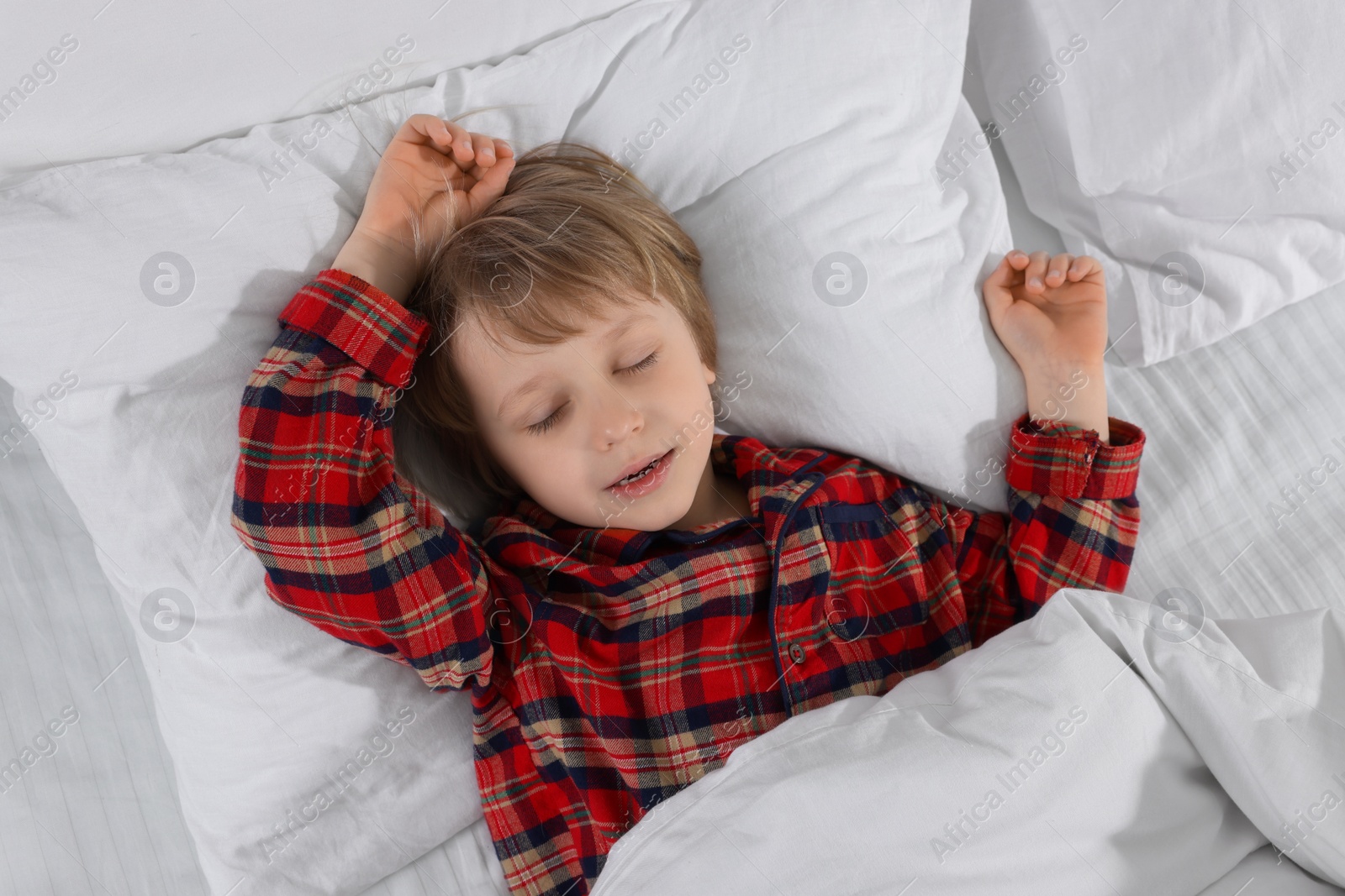 Photo of Little boy snoring while sleeping in bed, top view