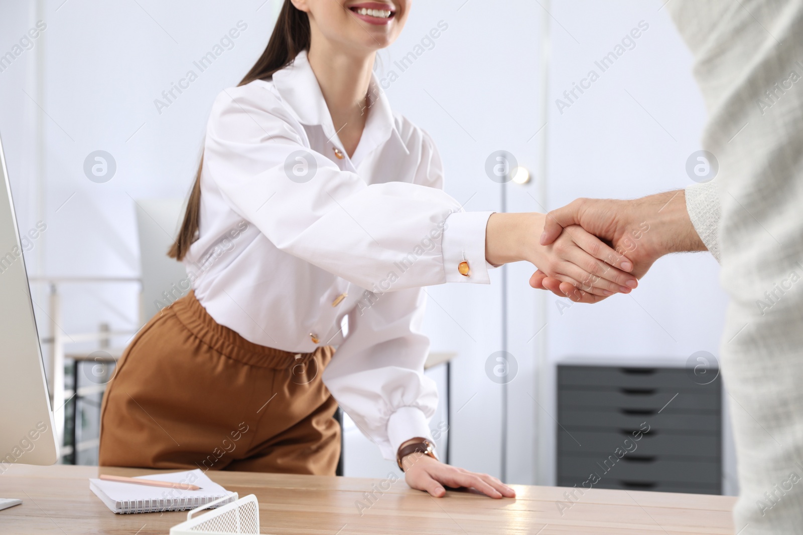 Photo of Employee shaking hands with intern in office, closeup