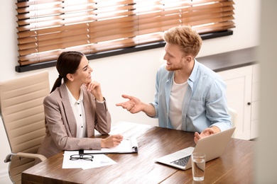 Female insurance agent consulting young man in office