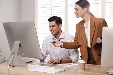 Businesswoman helping intern with work in office