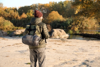 Photo of Male camper with backpack and sleeping bag in wilderness. Space for text