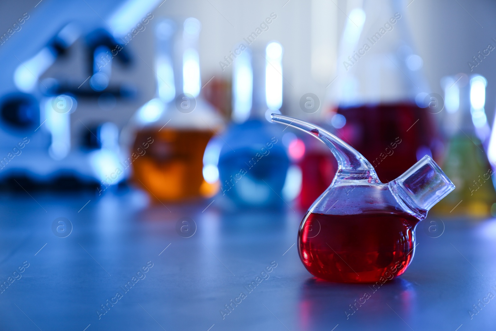 Photo of Retort flask on table against blurred background, space for text.  Chemistry glassware