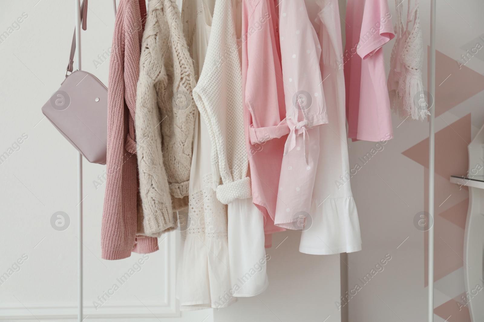 Photo of Rack with stylish clothes near white wall in dressing room