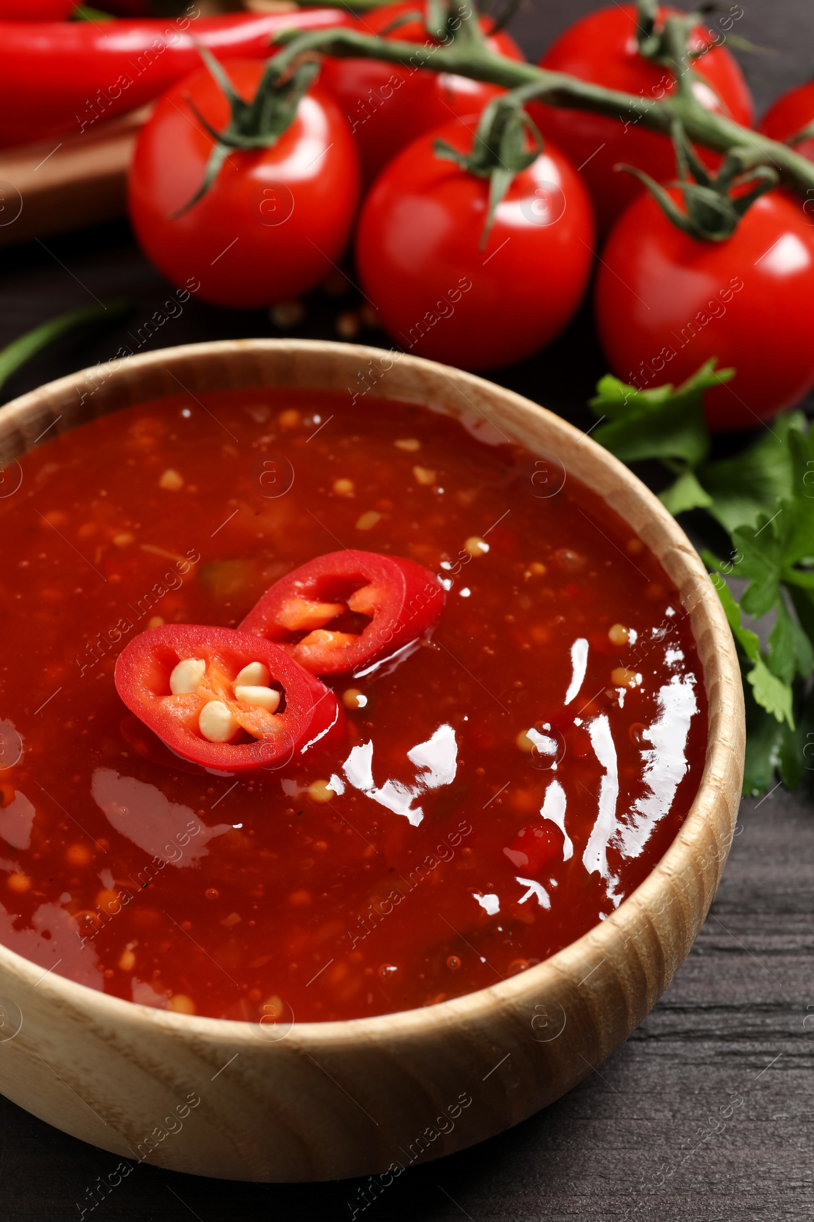 Photo of Spicy chili sauce in bowl on wooden table, closeup