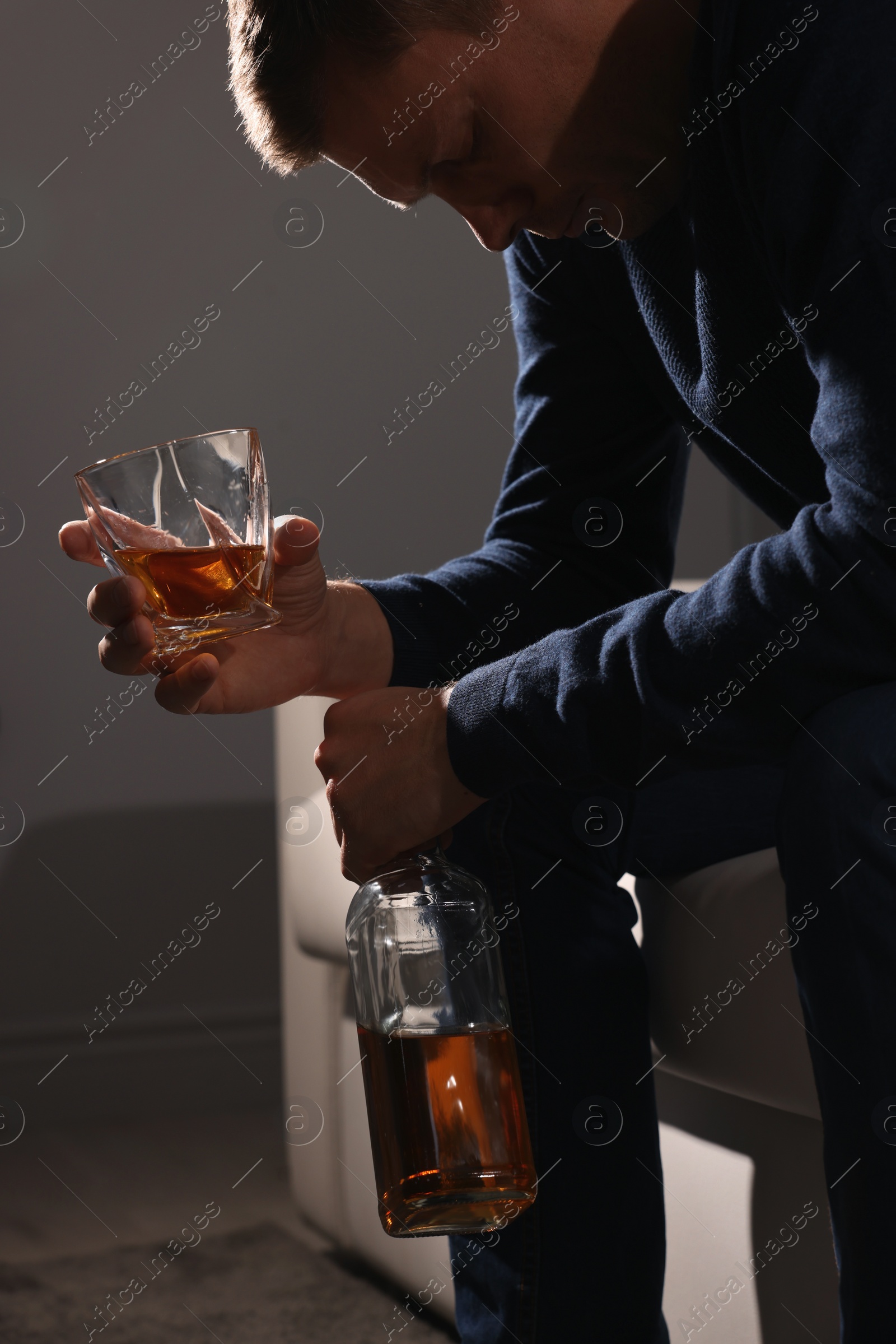 Photo of Addicted man with alcoholic drink on sofa indoors, closeup