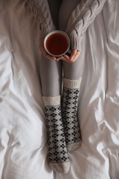 Photo of Woman with cup of tea on soft blanket, top view