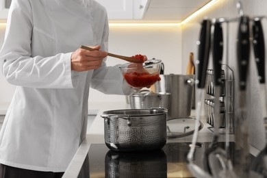 Photo of Professional chef cooking delicious dish in saucepan indoors, closeup