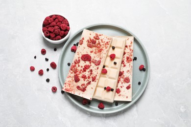 Photo of White chocolate bars with freeze dried fruits on grey marble table, flat lay