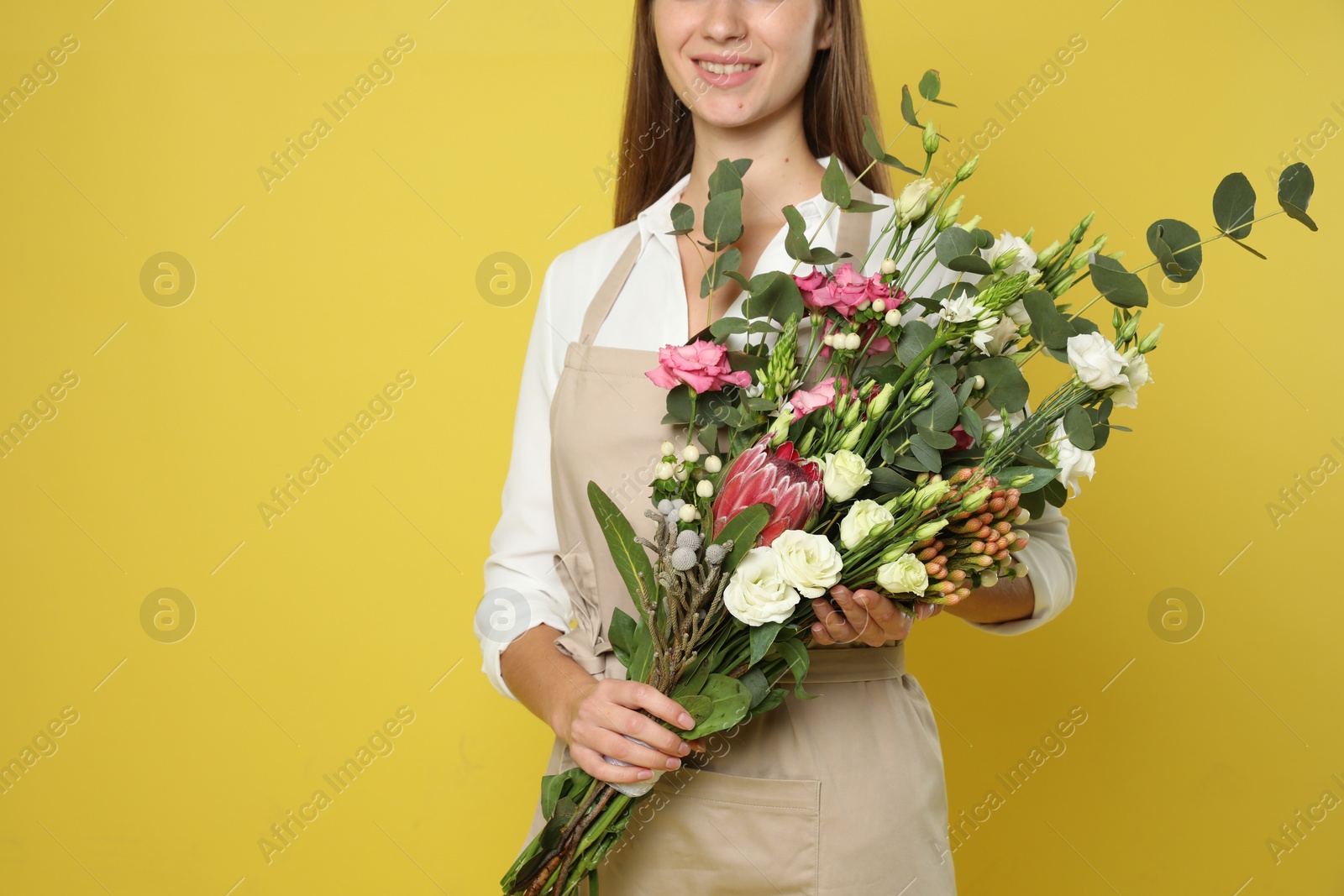 Photo of Florist with beautiful bouquet on yellow background, closeup. Space for text
