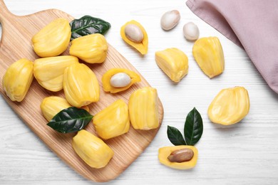 Delicious exotic jackfruit bulbs on white wooden table, flat lay