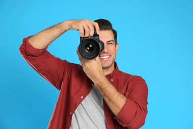 Photo of Professional photographer working on light blue background in studio