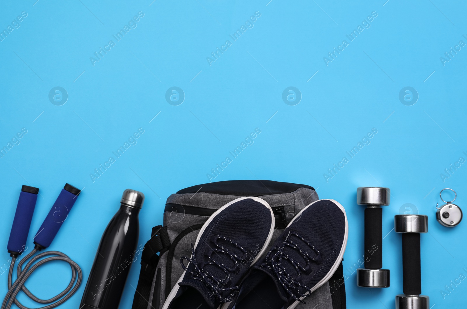 Photo of Gym bag and sports equipment on light blue background, flat lay. Space for text