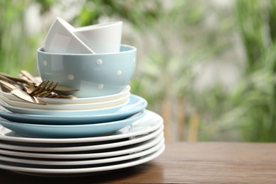 Photo of Beautiful ceramic dishware and cutlery on wooden table outdoors, space for text