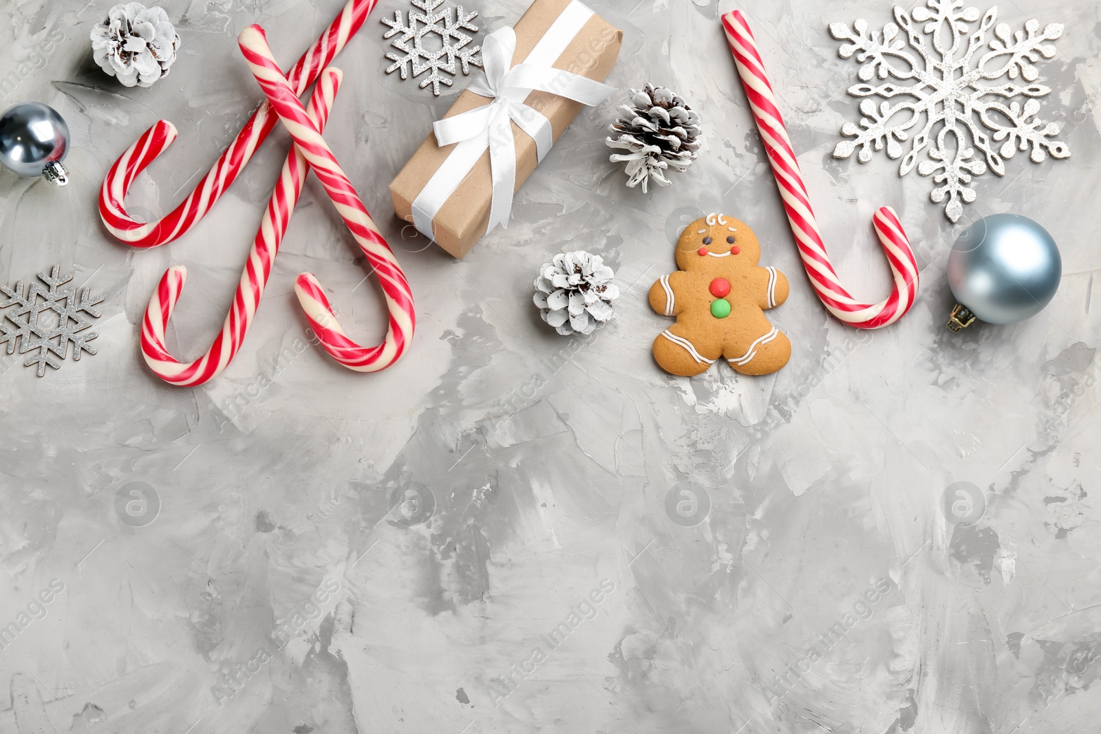 Photo of Flat lay composition with candy canes and Christmas decor on grey table. Space for text