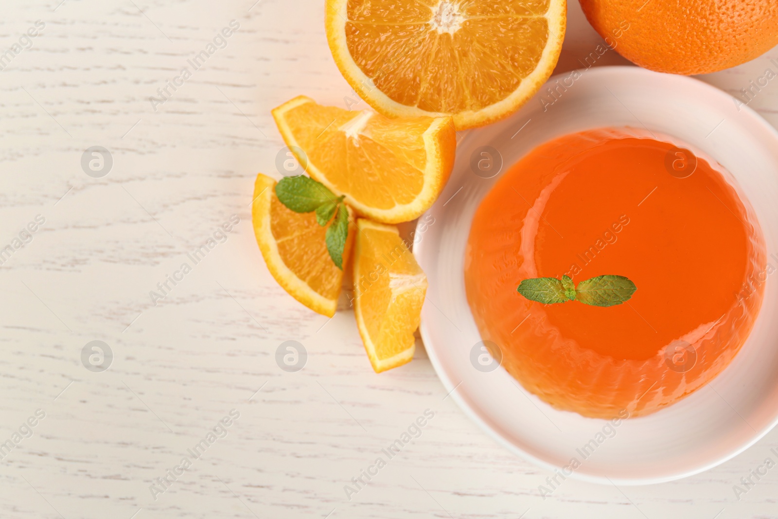 Photo of Flat lay composition of tasty jelly and oranges on white wooden table, space for text