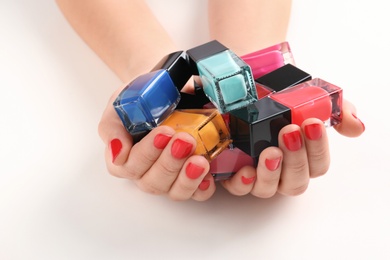 Woman holding nail polish bottles on white background, closeup