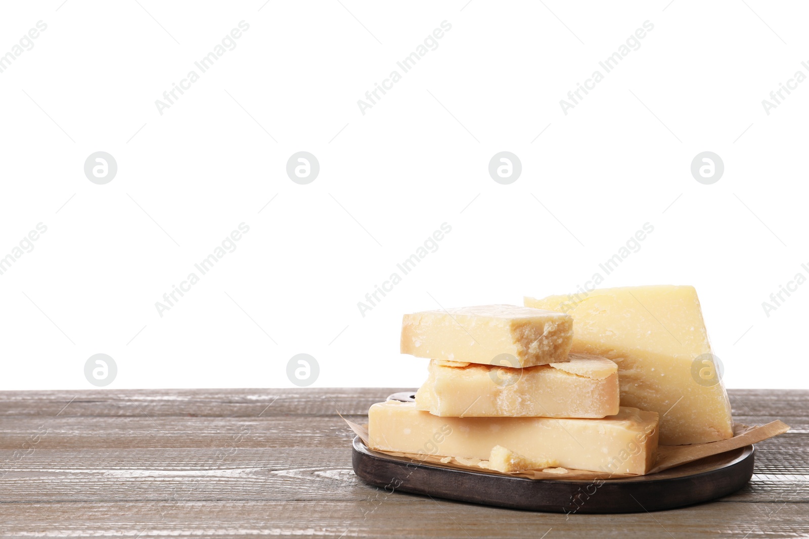 Photo of Pieces of delicious parmesan cheese on wooden table against white background. Space for text