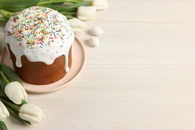 Photo of Delicious Easter cake with sprinkles and beautiful tulips on white wooden table. Space for text