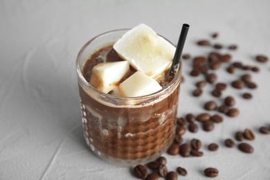 Photo of Coffee drink with milk ice cubes and beans on grey table