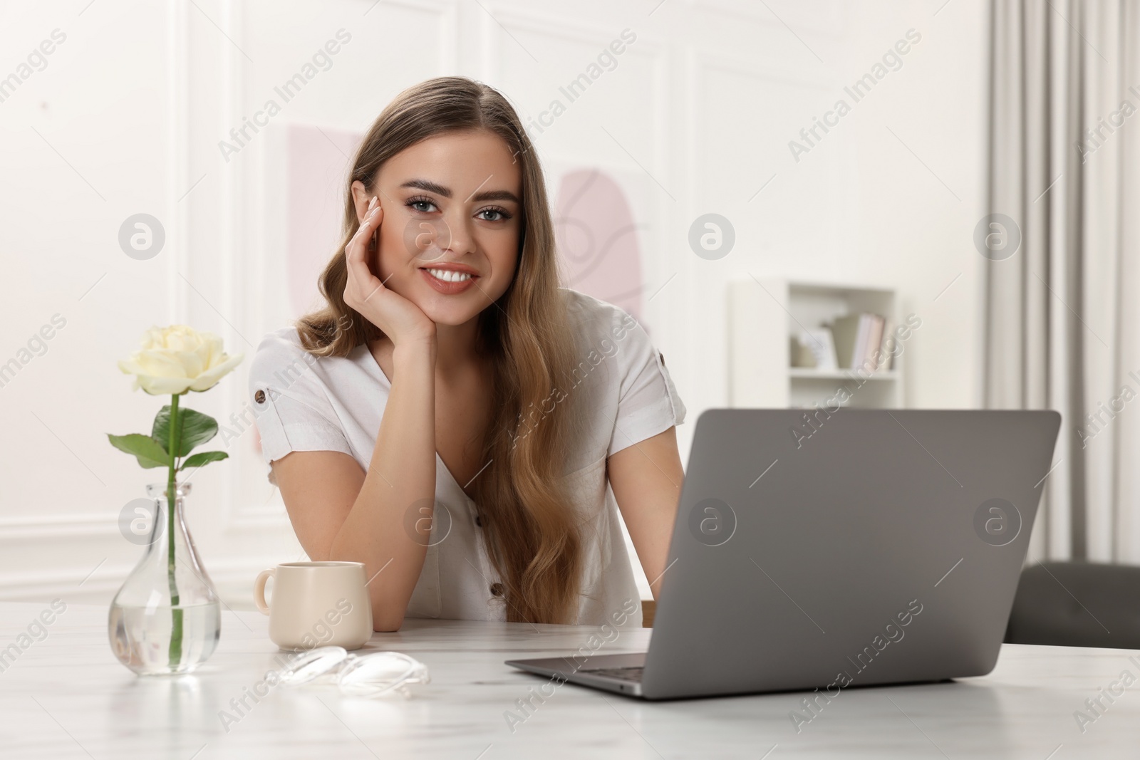 Photo of Happy woman with laptop at white table