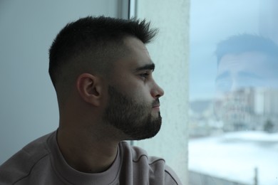 Sad man looking at window at home