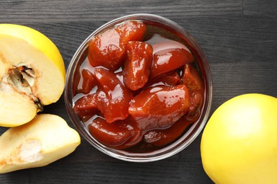 Quince jam in glass bowl and fresh raw fruits on grey wooden table, flat lay