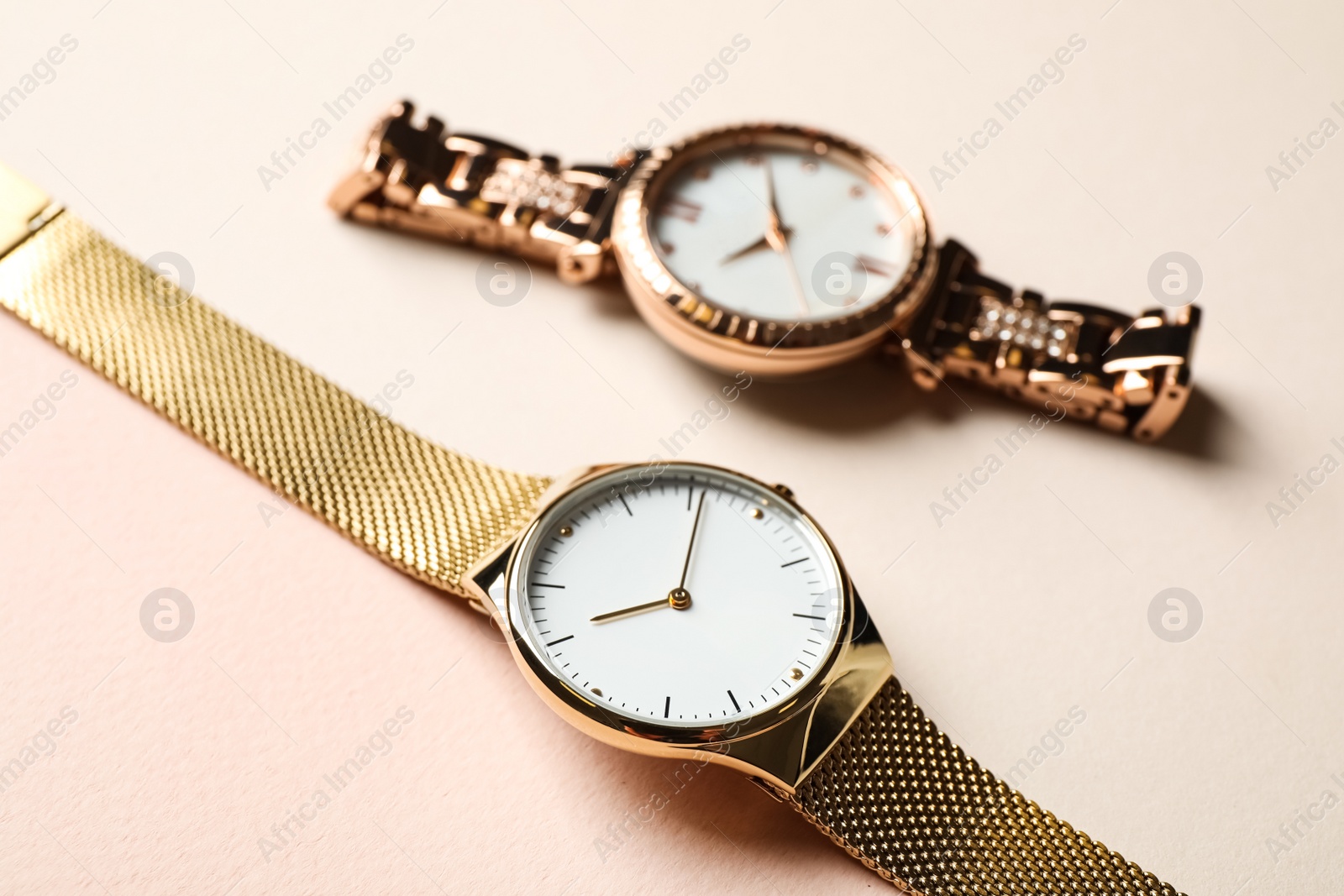 Photo of Luxury wrist watches on beige background, closeup