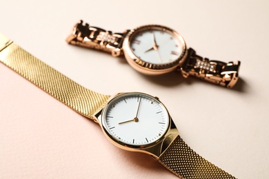 Photo of Luxury wrist watches on beige background, closeup