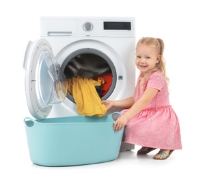 Photo of Cute little girl taking laundry out of washing machine on white background