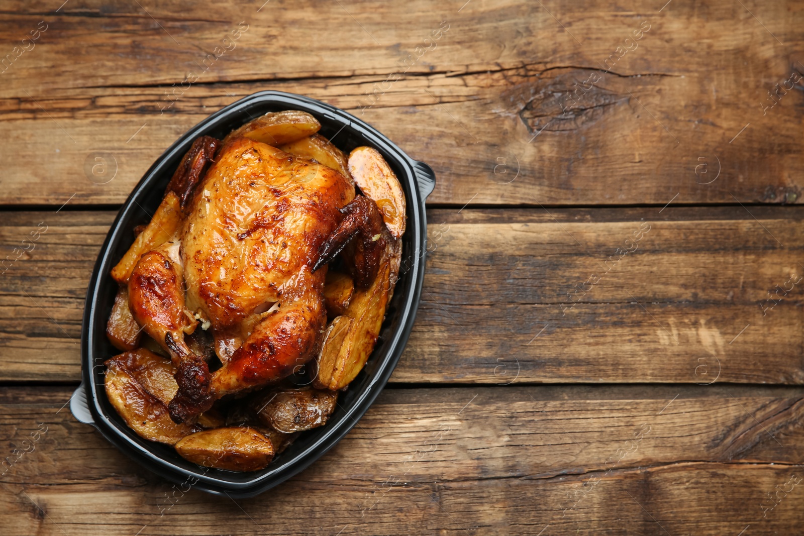 Photo of Top view of delicious grilled chicken with potato in plastic container on wooden table, space for text. Food delivery service