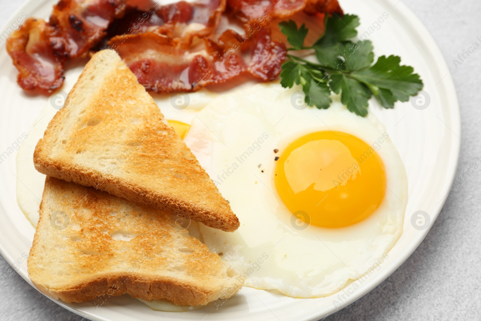 Photo of Delicious breakfast with sunny side up egg on light table, closeup