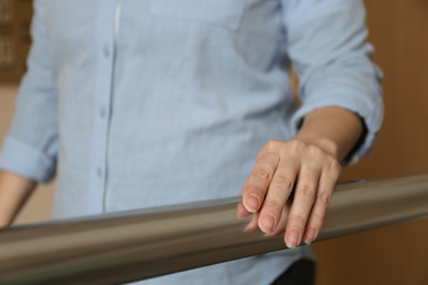 Photo of Woman leaning on metal railing indoors, closeup