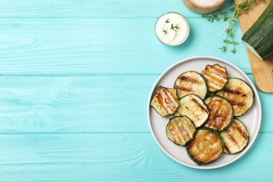 Photo of Plate of delicious grilled zucchini slices on light blue wooden table, flat lay. Space for text