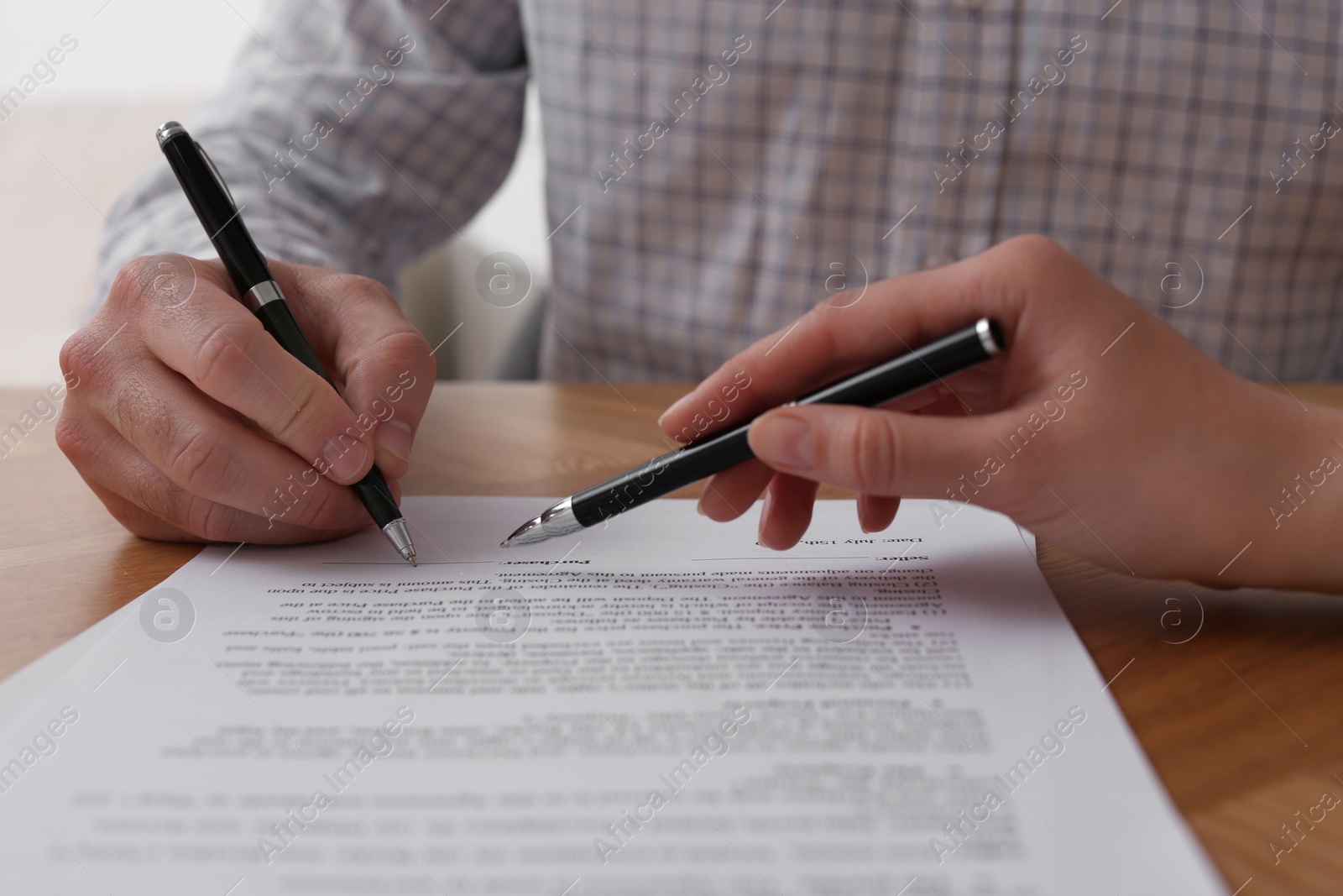 Photo of Businesspeople signing contract at wooden table, closeup of hands