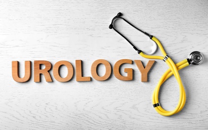 Photo of Word "UROLOGY" made with letters and stethoscope on wooden background, top view