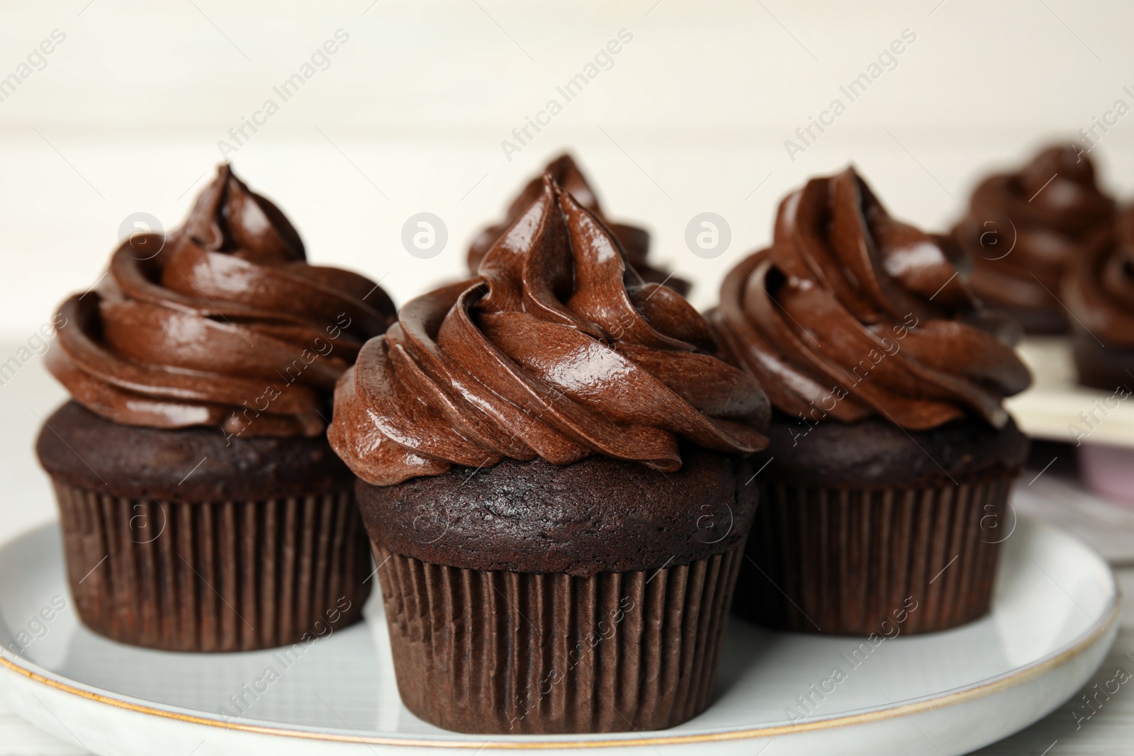 Photo of Delicious chocolate cupcakes with cream on plate, closeup