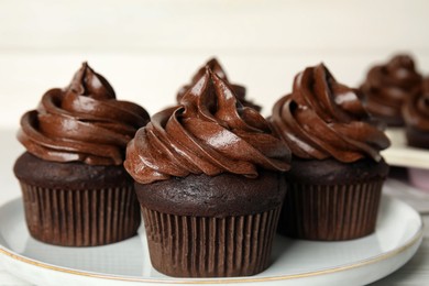 Delicious chocolate cupcakes with cream on plate, closeup