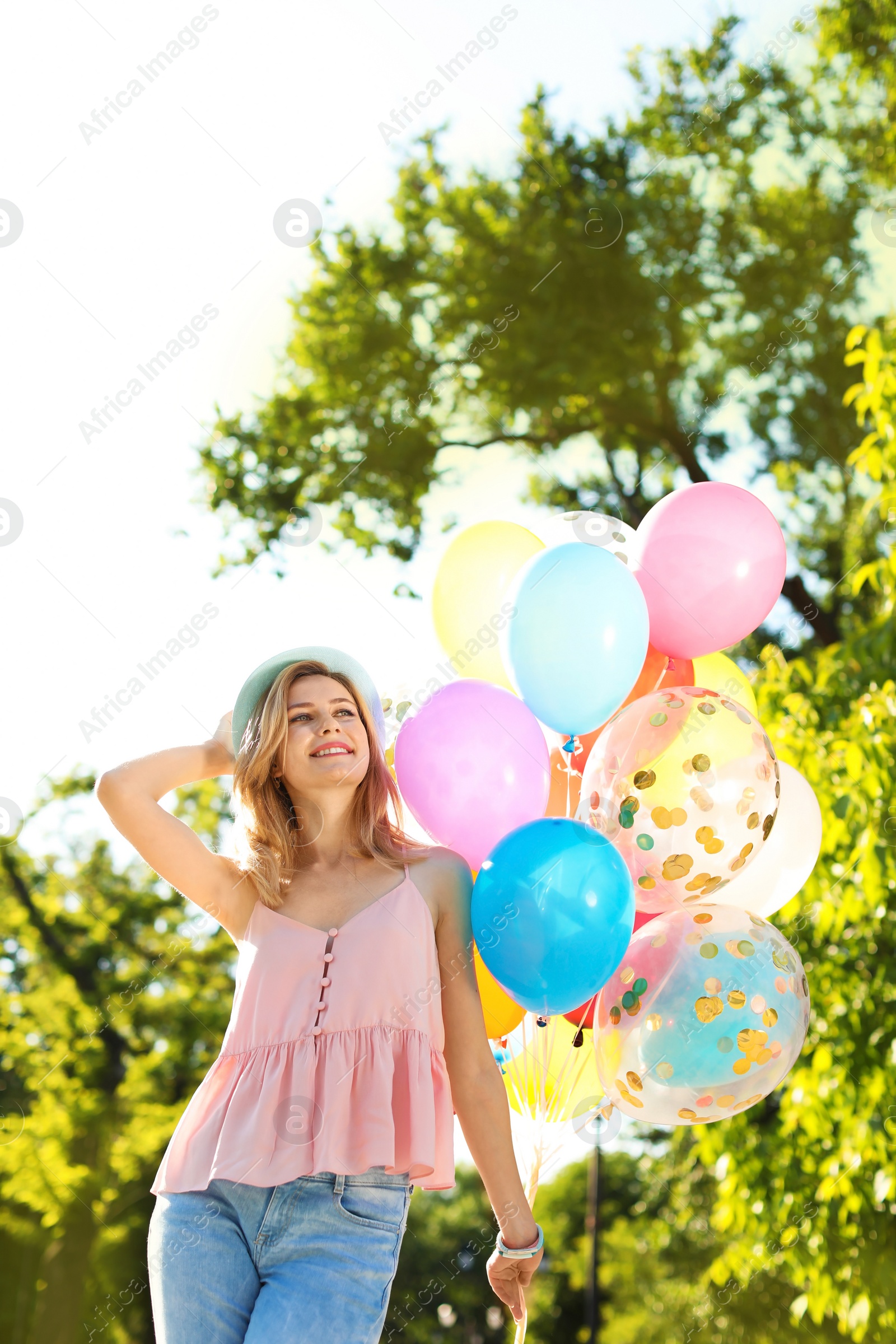 Photo of Young woman with colorful balloons outdoors on sunny day