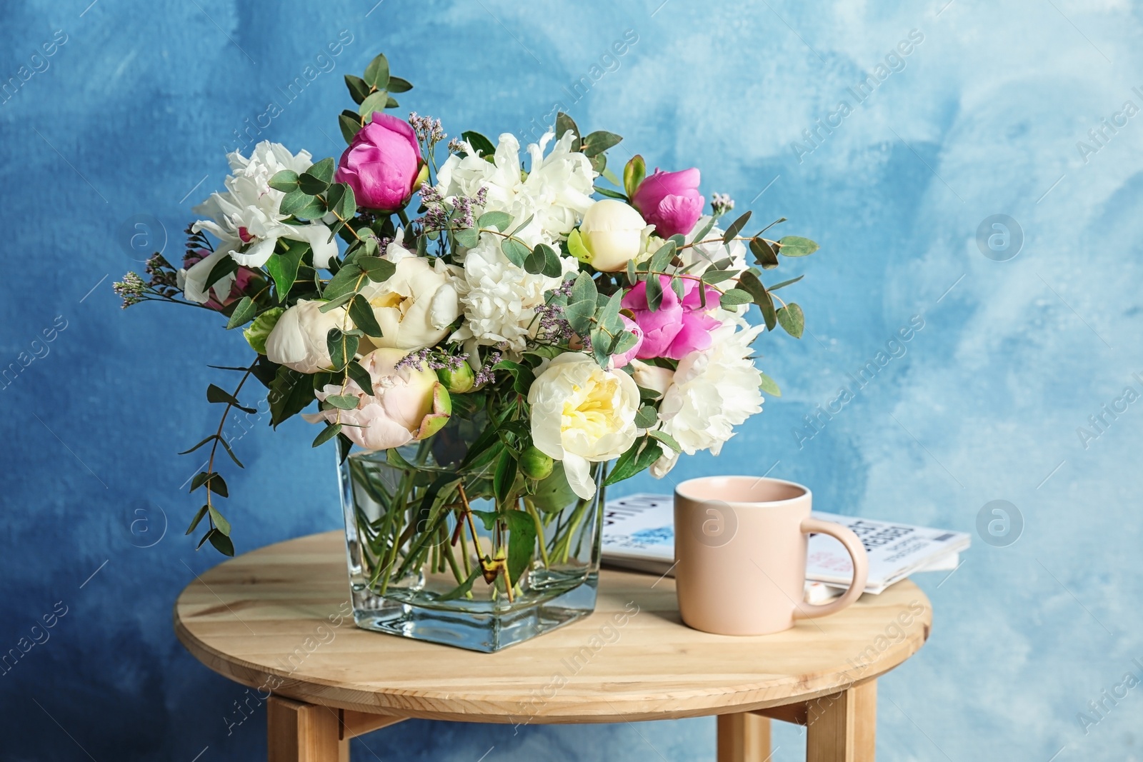 Photo of Vase with bouquet of beautiful flowers and cup on table