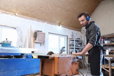 Young working man using circular saw at carpentry shop