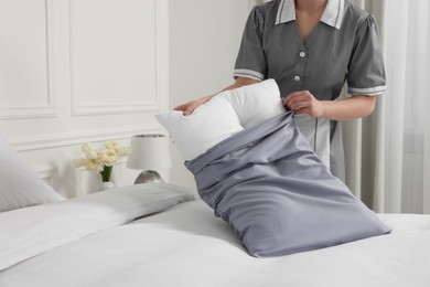 Photo of Chambermaid making bed in hotel room, closeup