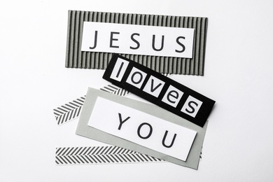 Printed words JESUS LOVES YOU on white background, top view