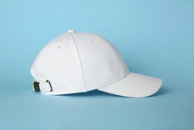 Photo of Stylish white baseball cap on light blue background